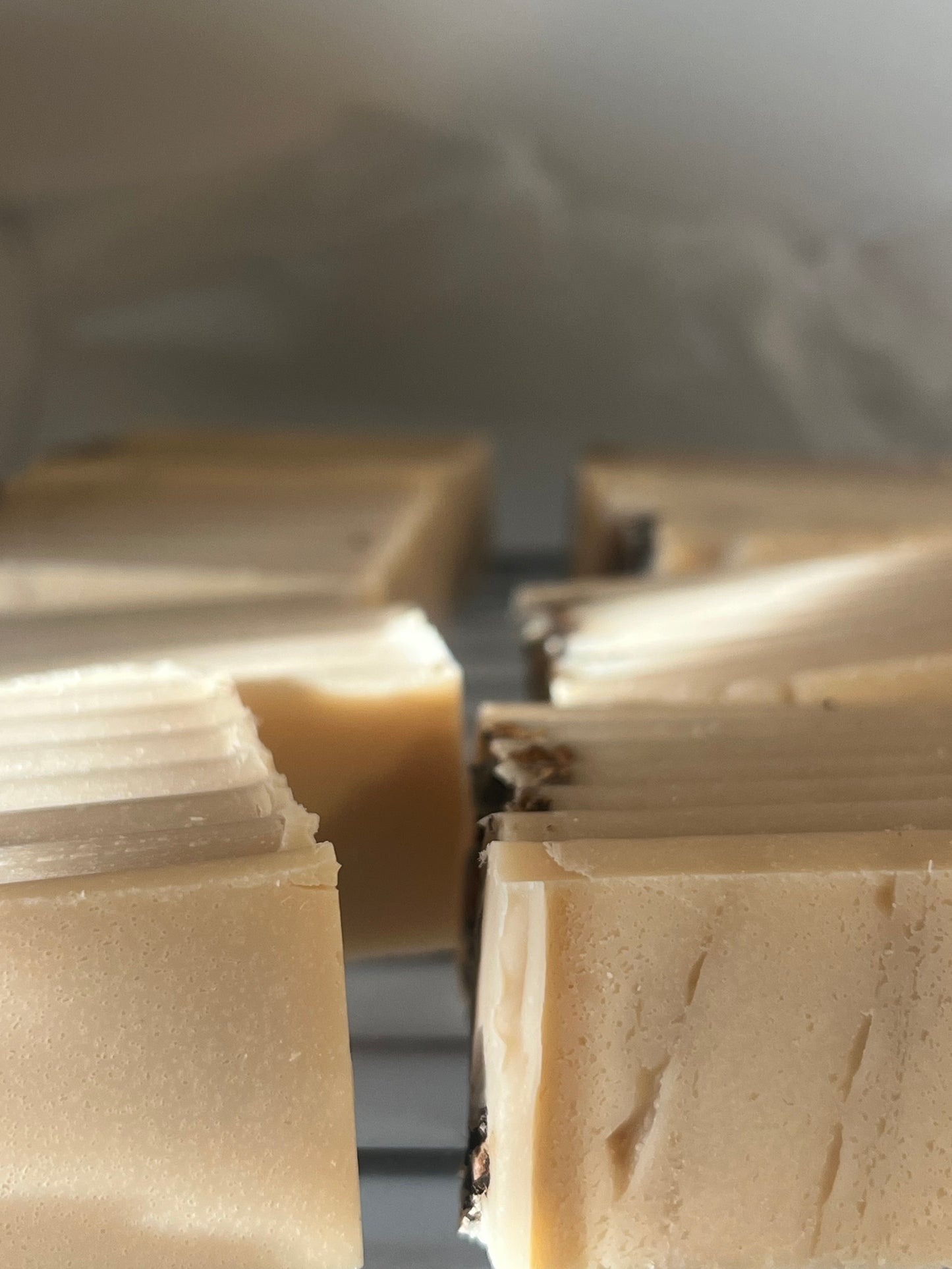 Rows of freshly cut, pale yellow homemade soap bars cool on a wire rack.