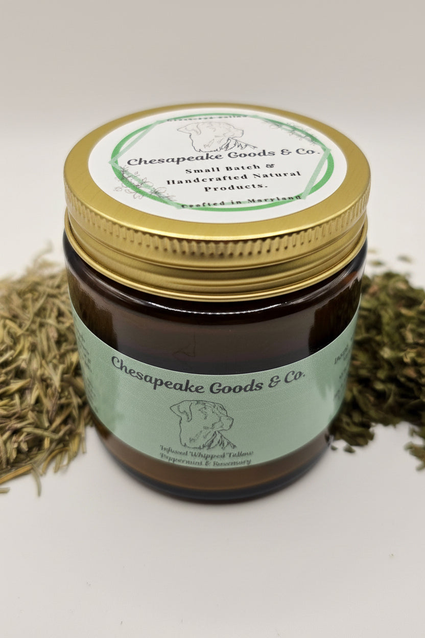Chesapeake Goods & Co. sells its handcrafted peppermint rosemary tallow balm in an amber jar surrounded by dried peppermint and rosemary.
