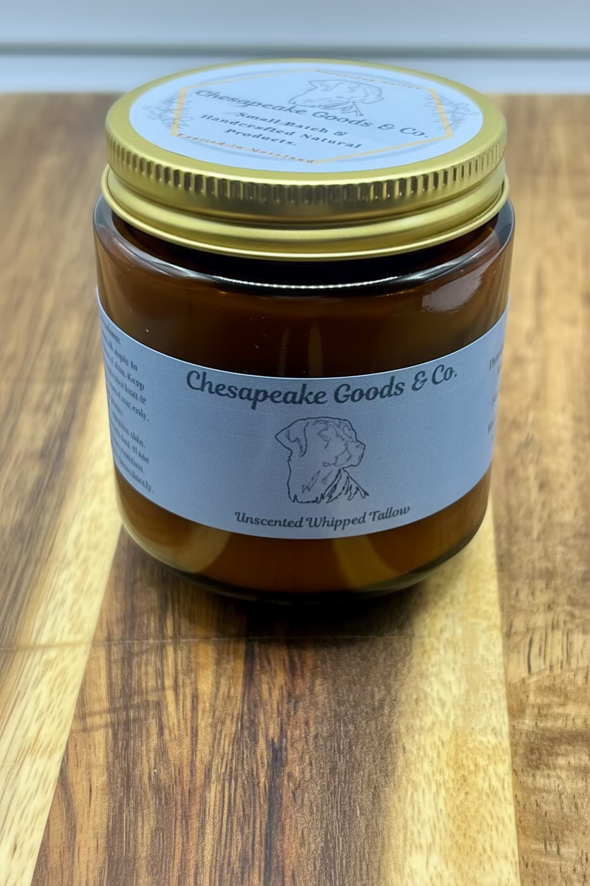 A 4 oz jar of Chesapeake Goods & Co. Unscented Whipped Tallow sits on a wooden surface, displaying its handcrafted, natural skincare product.
